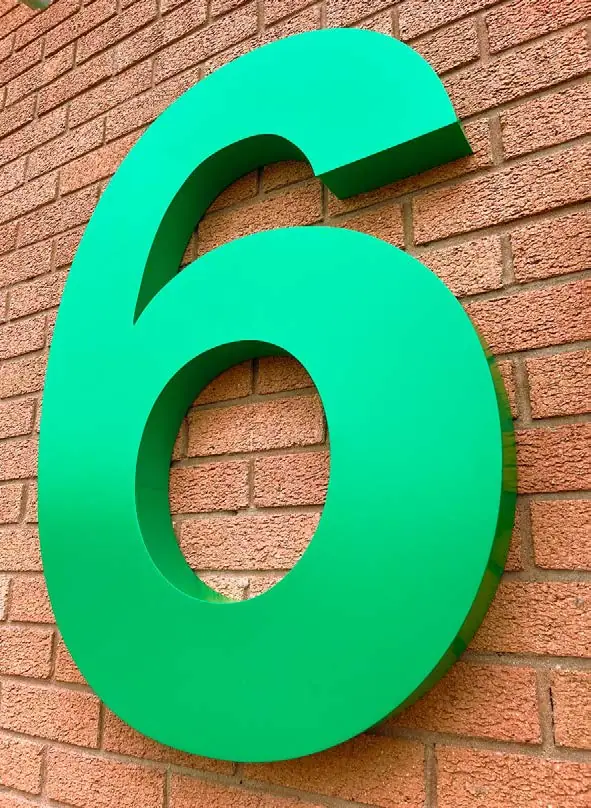 Giant green built-up number 6 on brickwork