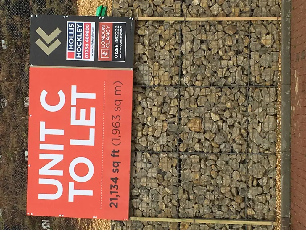 Tall 'Unit C to let' sign on gabion wall
