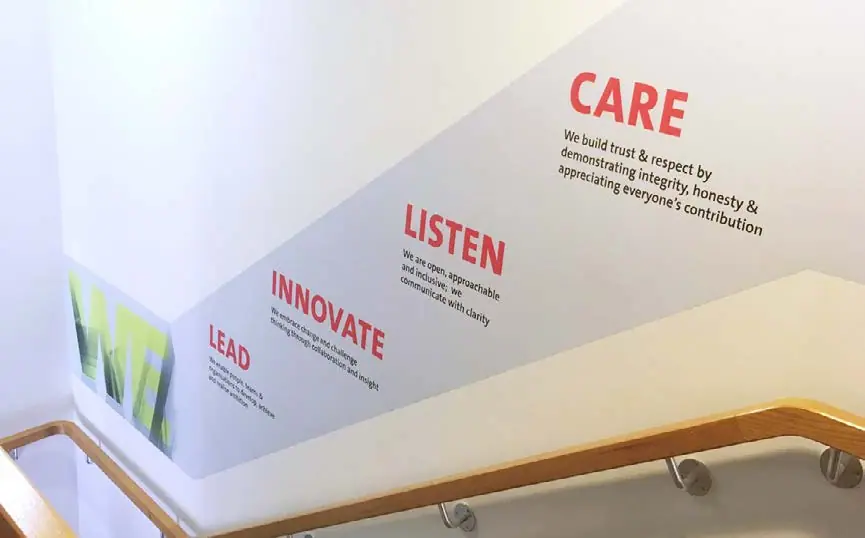 Office wall graphics reading 'care', 'listen', 'innovate'