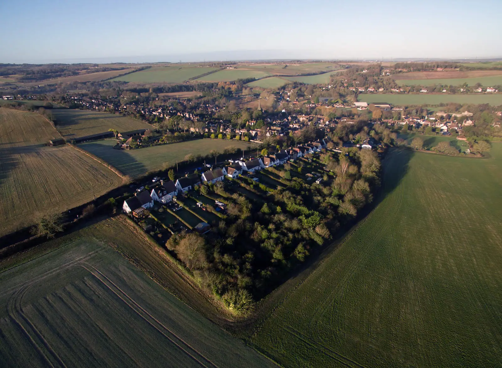 Low-angle drone shot along the edge of the site and neighbouring housing