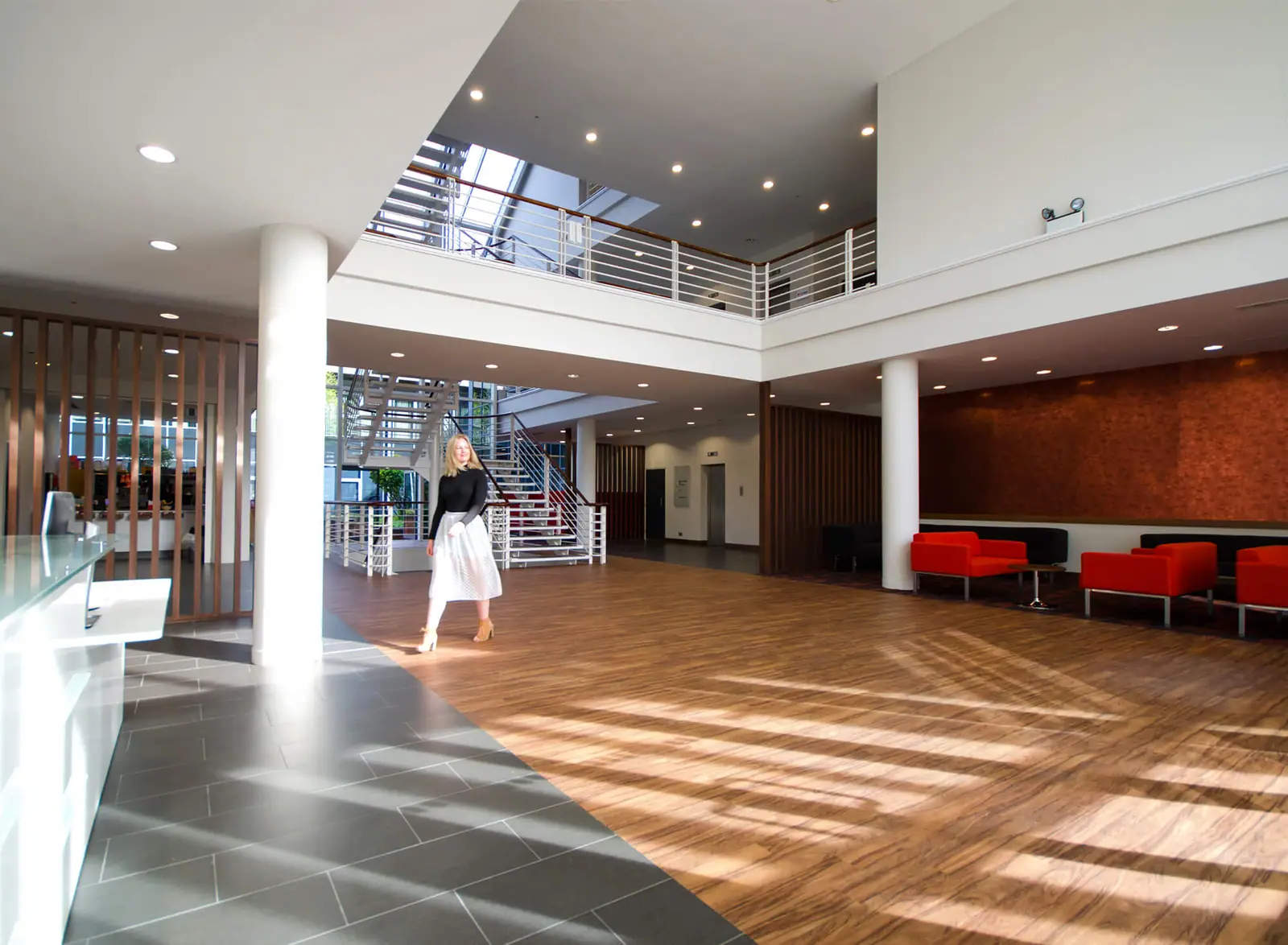 Double-height office reception at Broadlands with red sofas