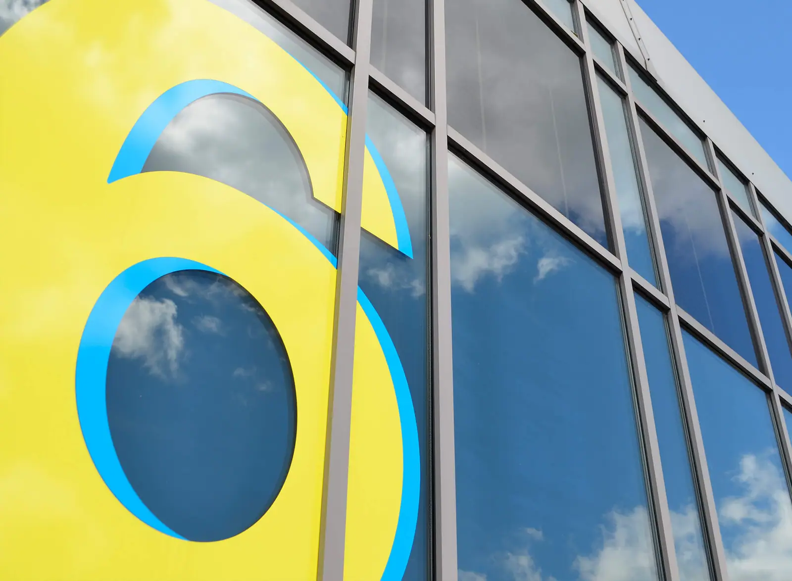 Large yellow and cyan vinyl number 6 on the building's glazing
