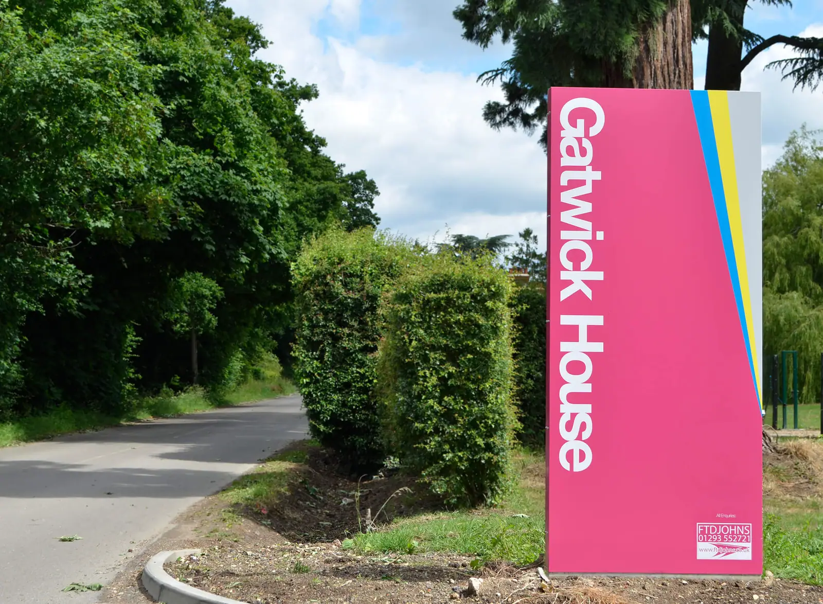 Tall magenta Gatwick House totem beside the estate road