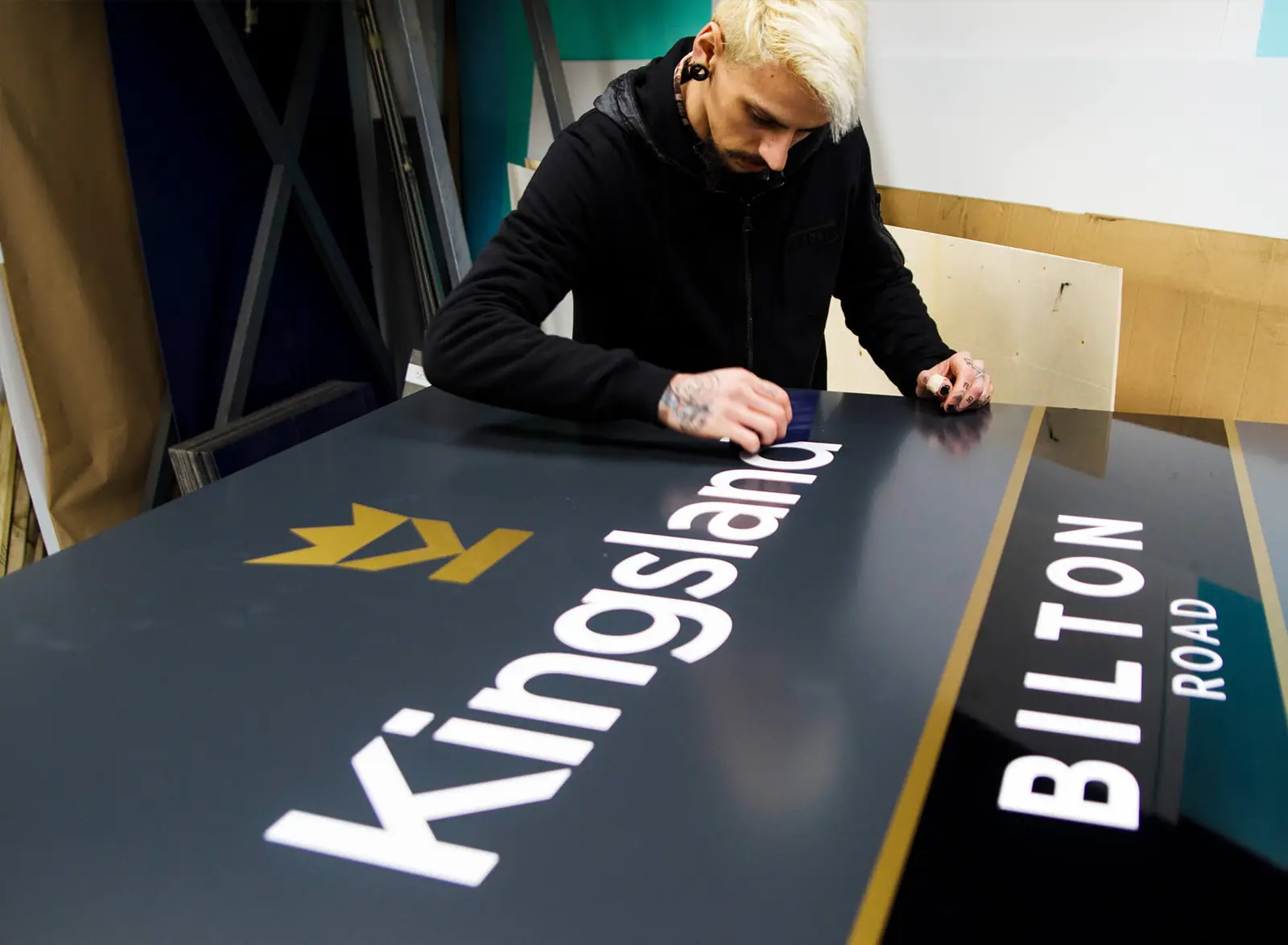Applying vinyl graphics to a Kingsland road sign in the workshop